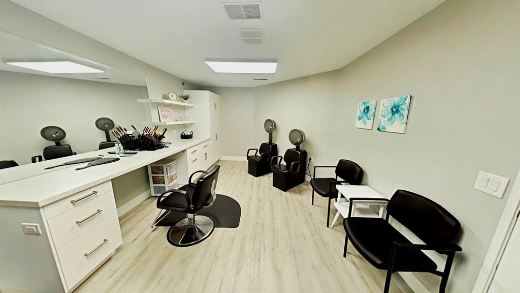 A room with a white desk and black chairs.