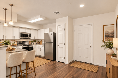 A kitchen with white cabinets and a stainless steel refrigerator.