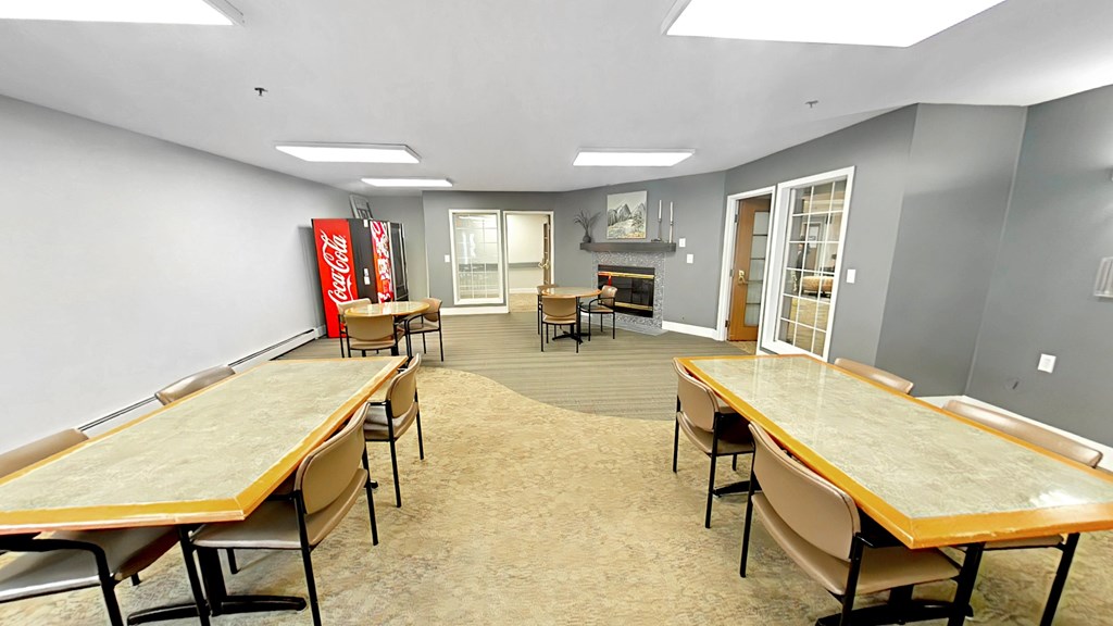 A room with tables and chairs and a Coca-Cola sign on the wall.