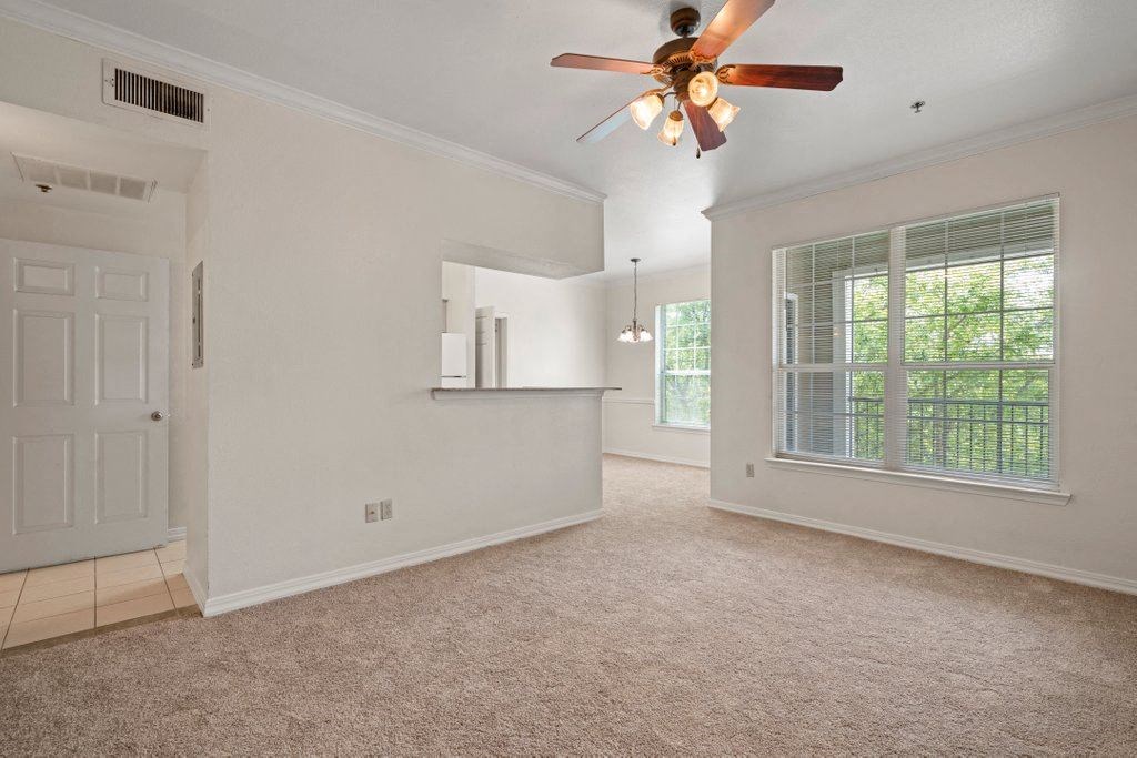 an empty living room with a ceiling fan and a window
