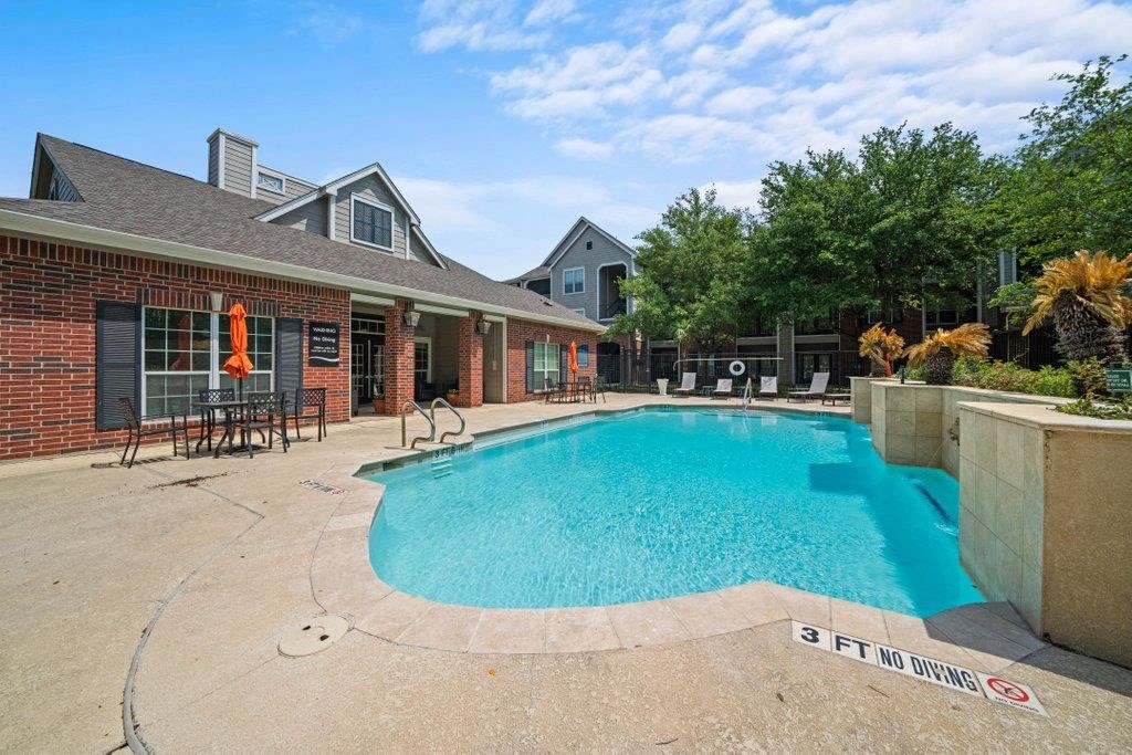 a swimming pool in front of a house with a brick building