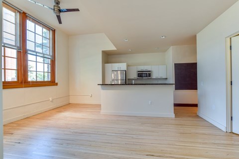 A spacious kitchen with a ceiling fan and wooden floors.