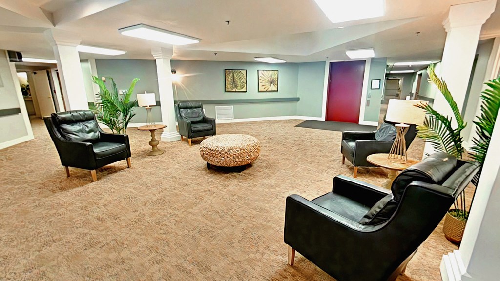 A living room with black leather chairs and a brown carpet.