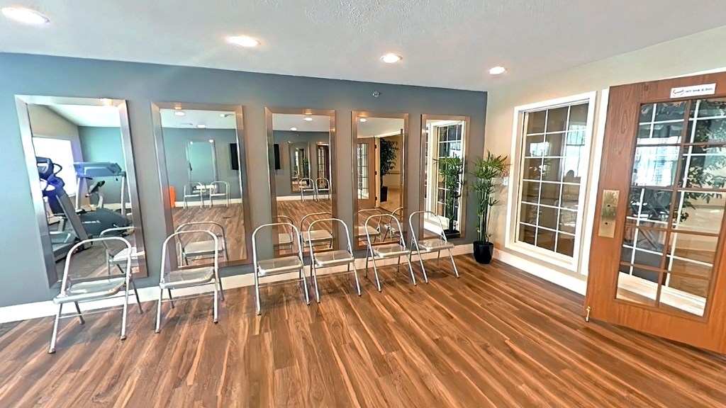 A room with a row of chairs and mirrors on the wall.