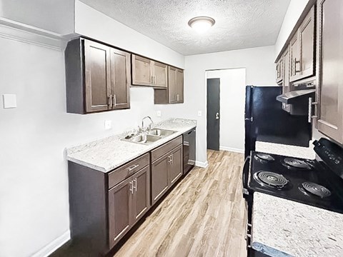 A kitchen with dark brown cabinets and a black stove top oven.