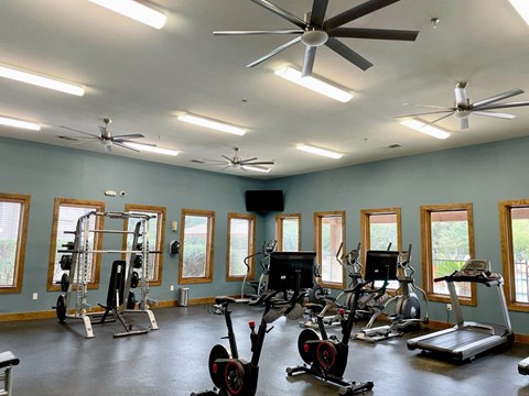 A spacious gym with a variety of equipment and a ceiling fan.