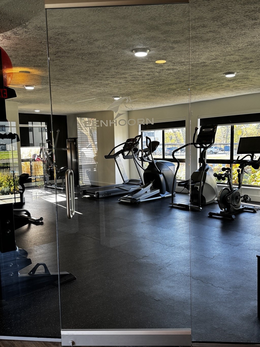A gym with a variety of exercise equipment including treadmills, stationary bikes, and weight machines.