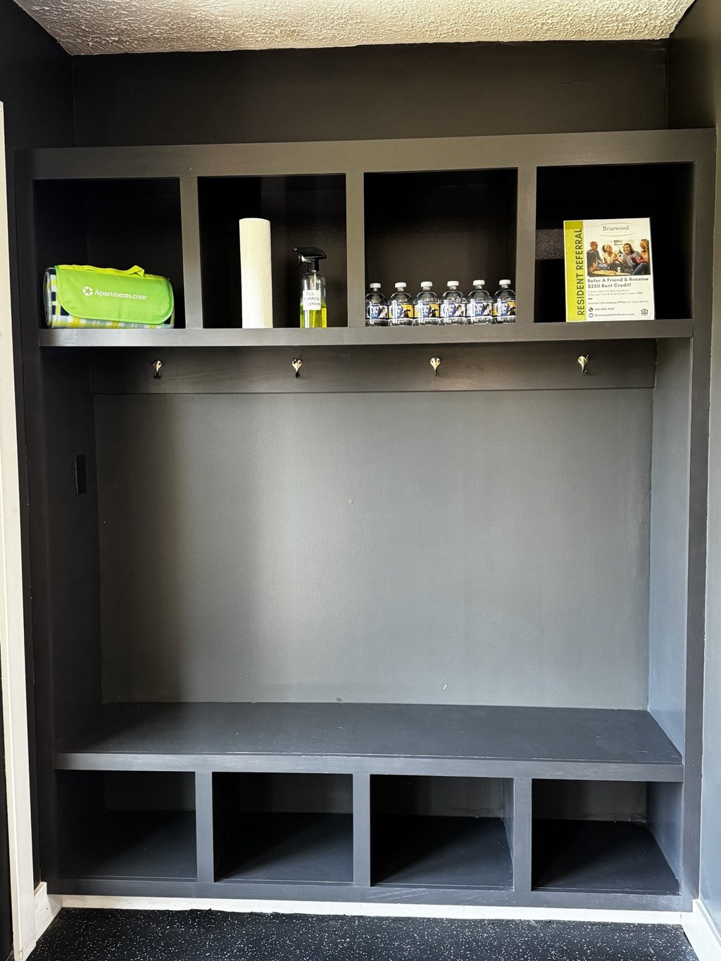 A grey shelf with a green bag and some bottles on it.