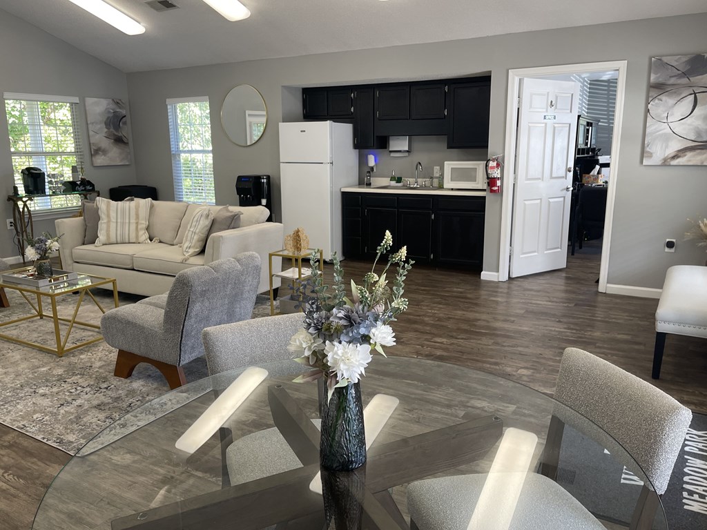A modern living room with a glass table and grey chairs.
