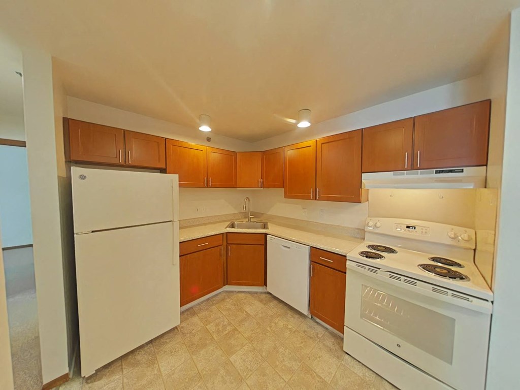 A kitchen with white appliances and brown cabinets.