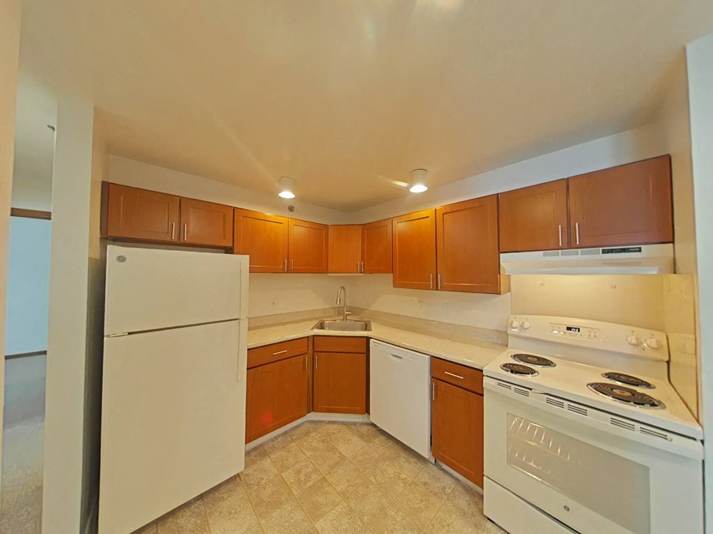 A kitchen with white appliances and brown cabinets.