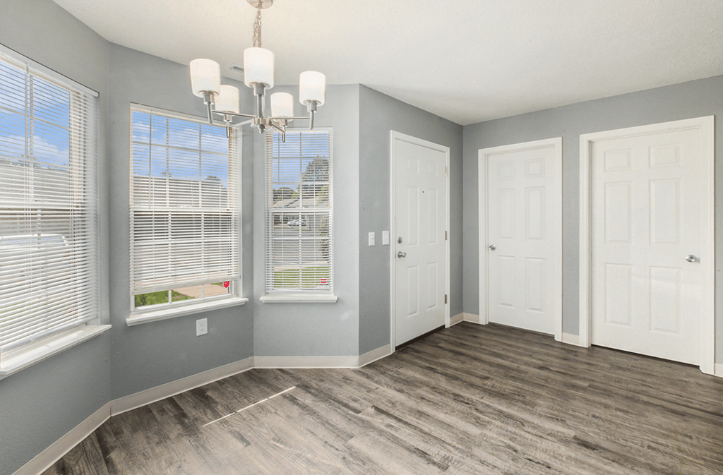 an empty room with three windows and a chandelier