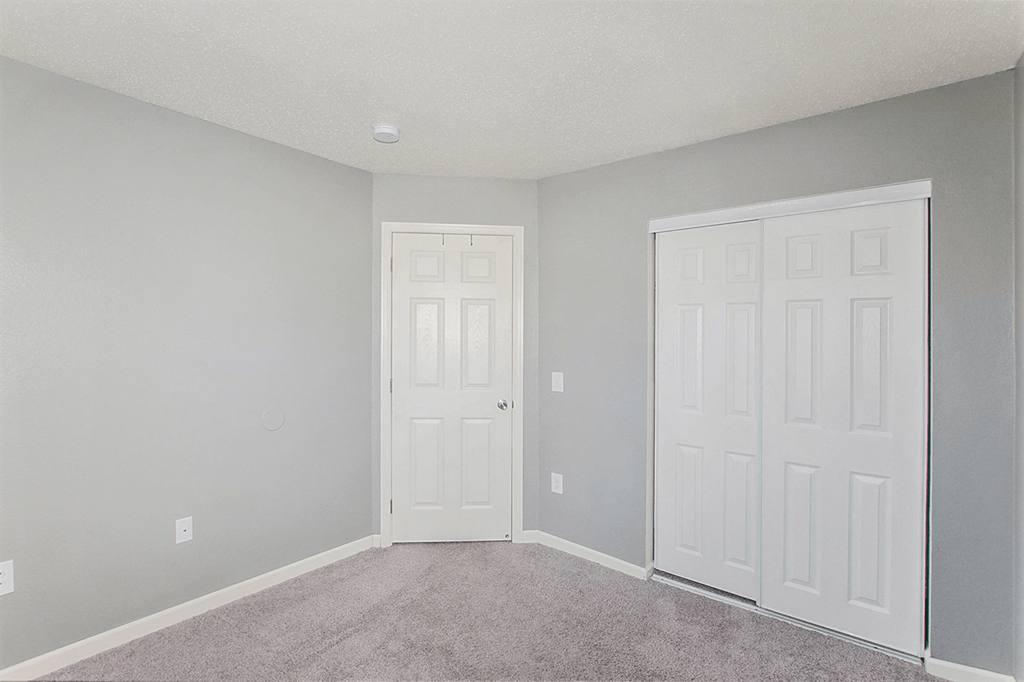 a bedroom with two doors and a carpeted floor