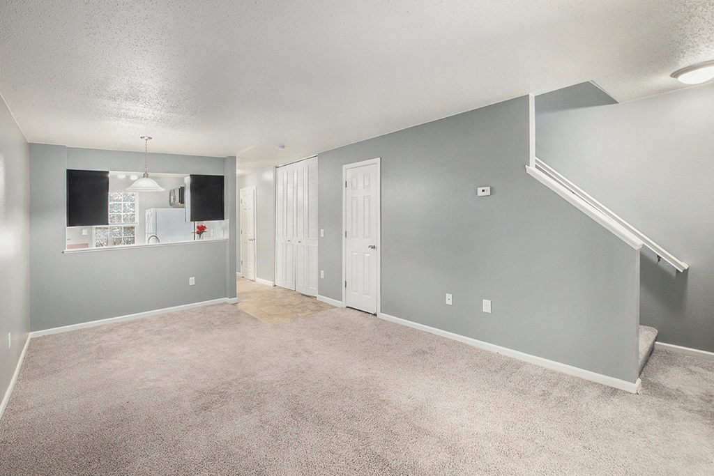 a living room with a staircase and a kitchen in the background