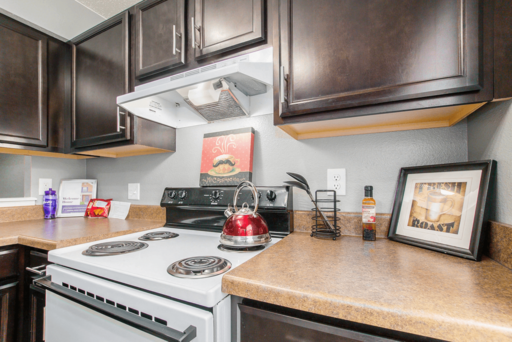 a kitchen with a stove top oven next to a counter top with a kettle on it