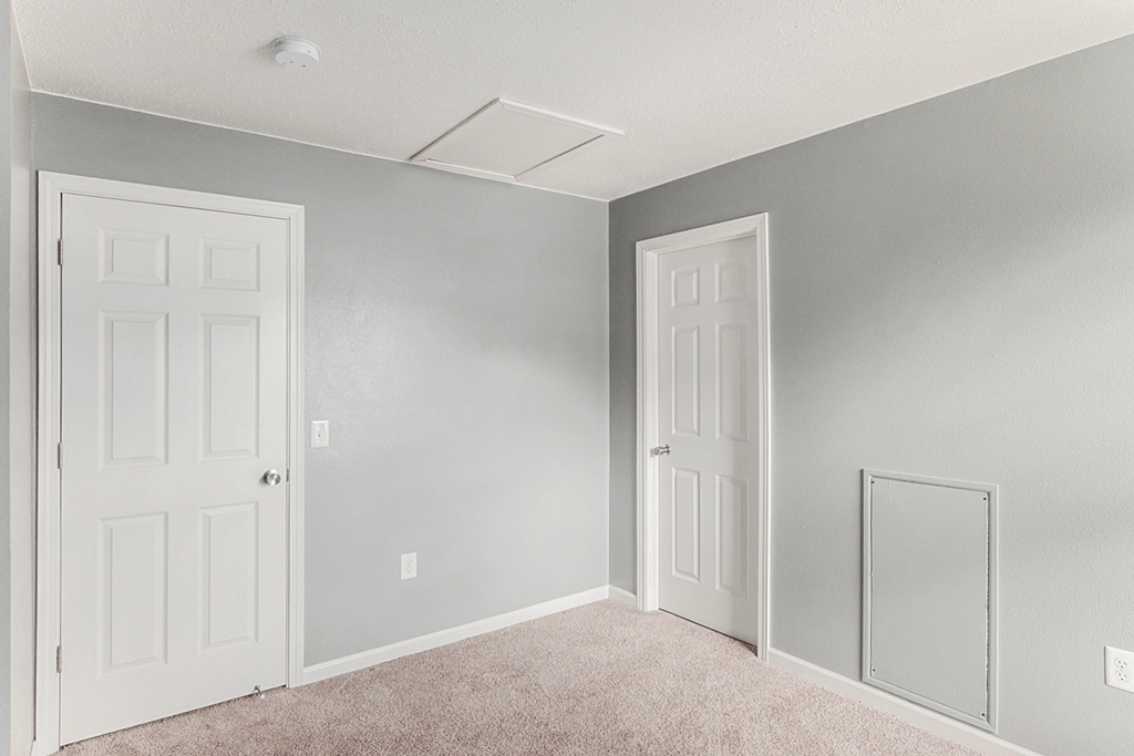 a bedroom with two doors and a mirror