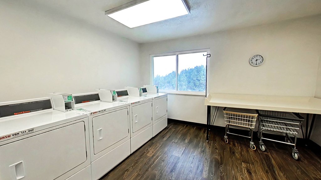 A laundry room with a row of washing machines and a clock on the wall.