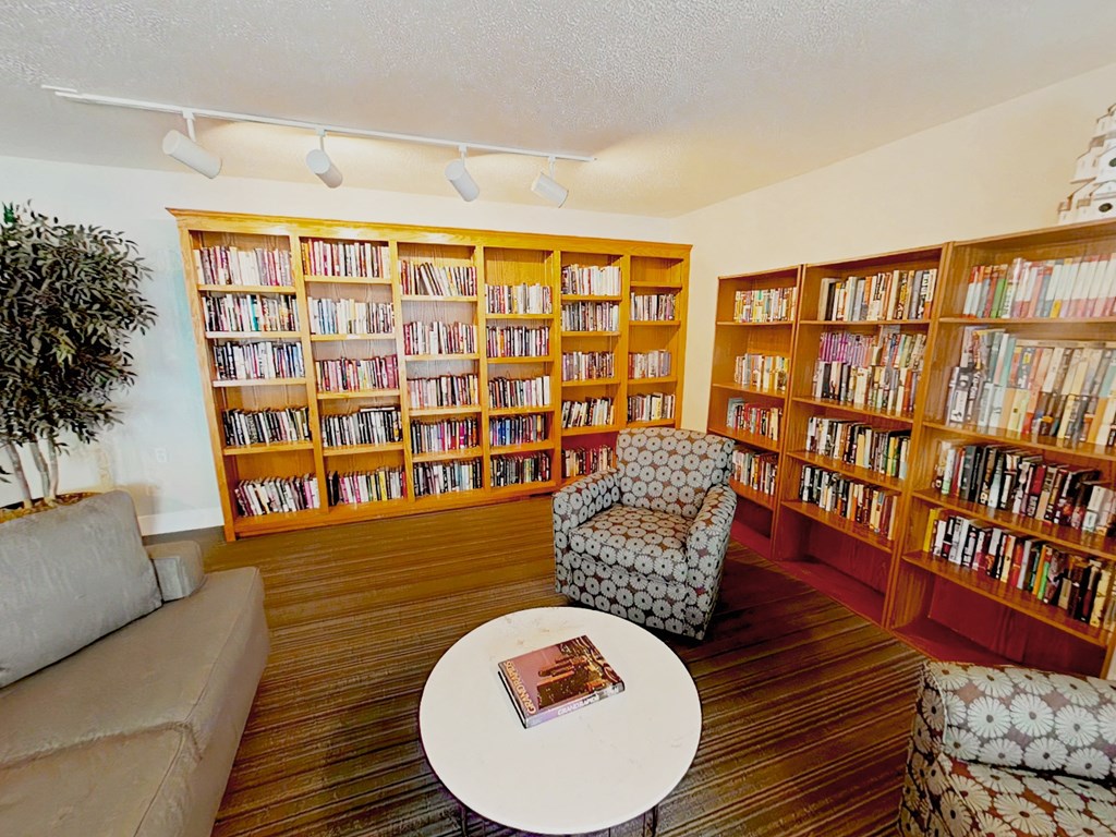 A living room with a couch, a chair, a coffee table, and a bookshelf filled with books.