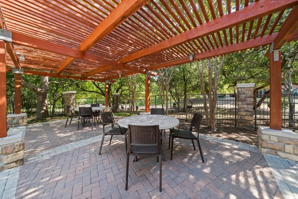 a patio with a pergola and a table and chairs