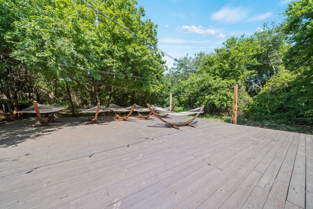 a deck with hammocks and trees in the background
