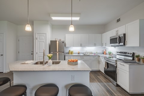 A kitchen with white cabinets and a large island with a sink.
