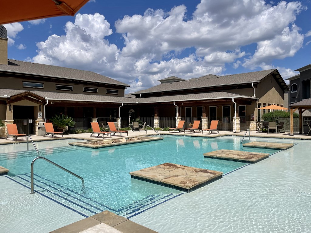a large pool with lounge chairs and a building in the background