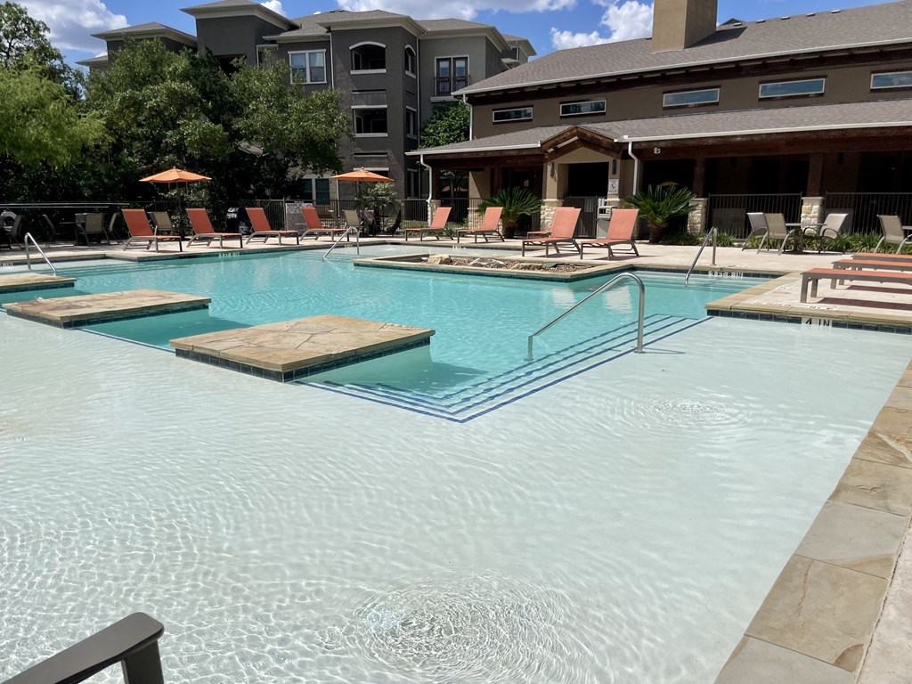 a swimming pool with a diving board in the middle of it and a hotel in the background