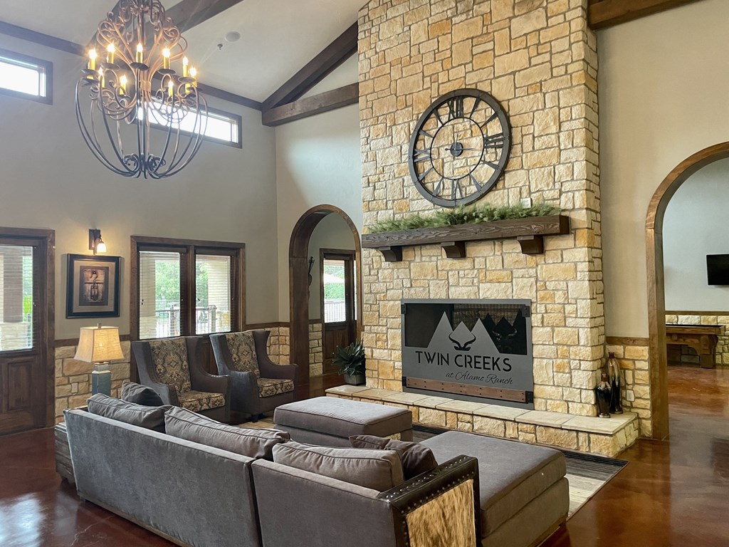 a living room with a large stone fireplace and a large clock on the wall