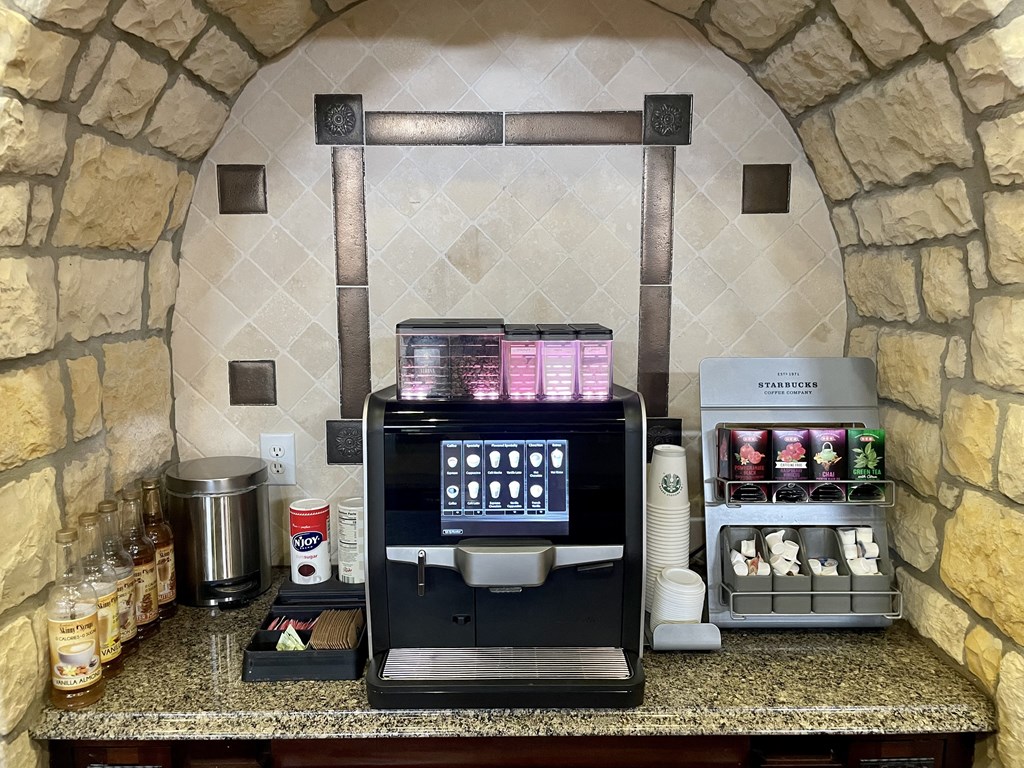a coffee maker and coffee cups on a counter in a hotel kitchen