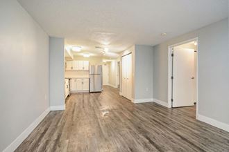 Spacious Dining Room with Hardwood Floors a spacious living room with a kitchen in the background