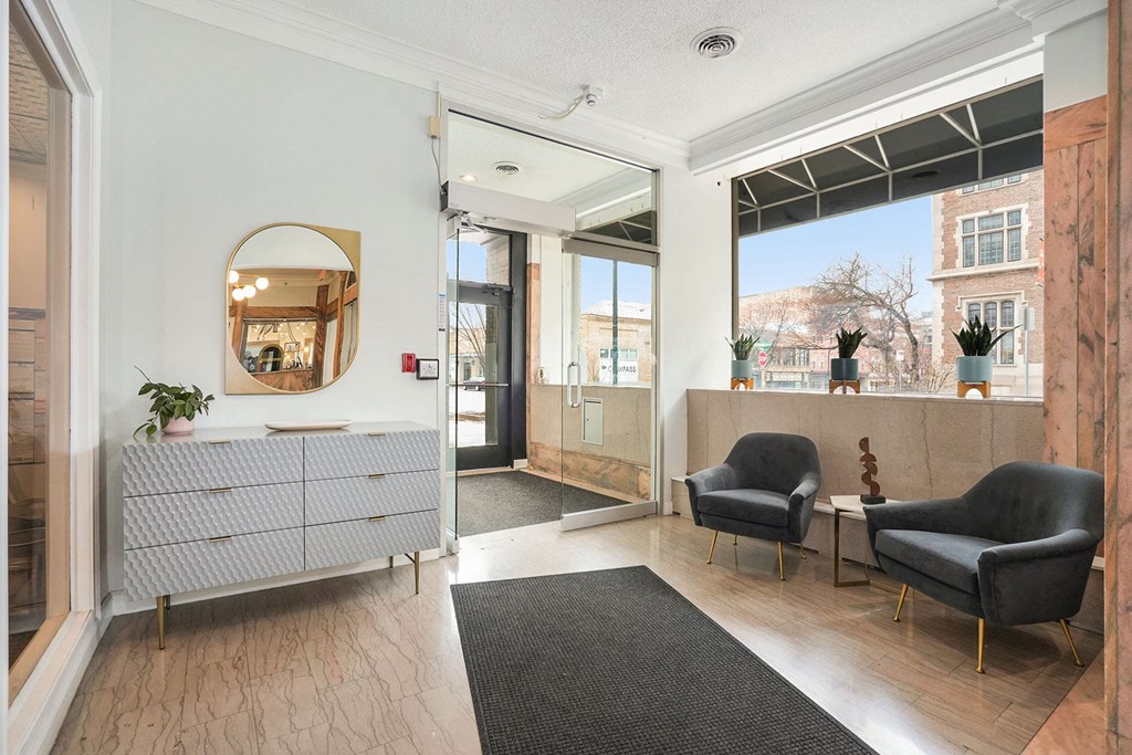 a lobby with two chairs and a credenza with a mirror on the wall
