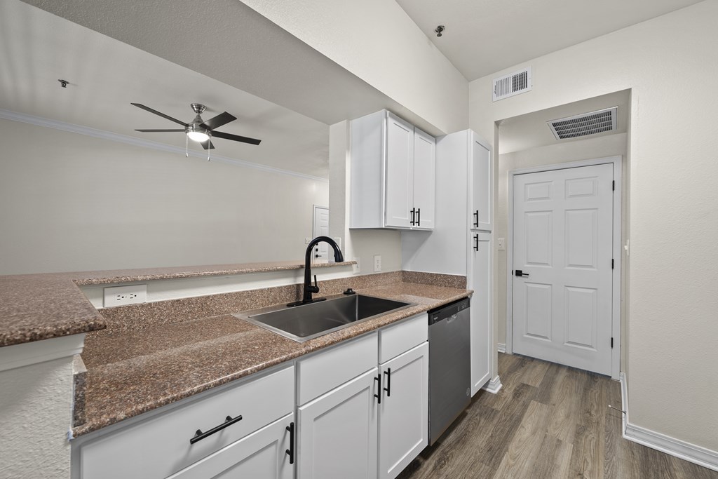 A kitchen with white cabinets and a granite countertop.