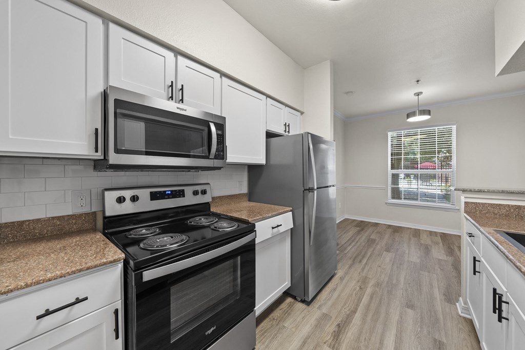 A kitchen with a stove, microwave, and refrigerator.
