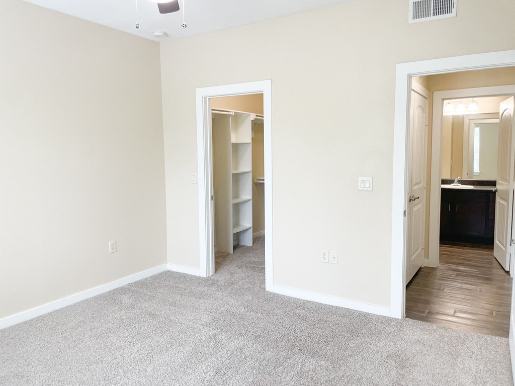a bedroom with a closet and a bathroom in the background