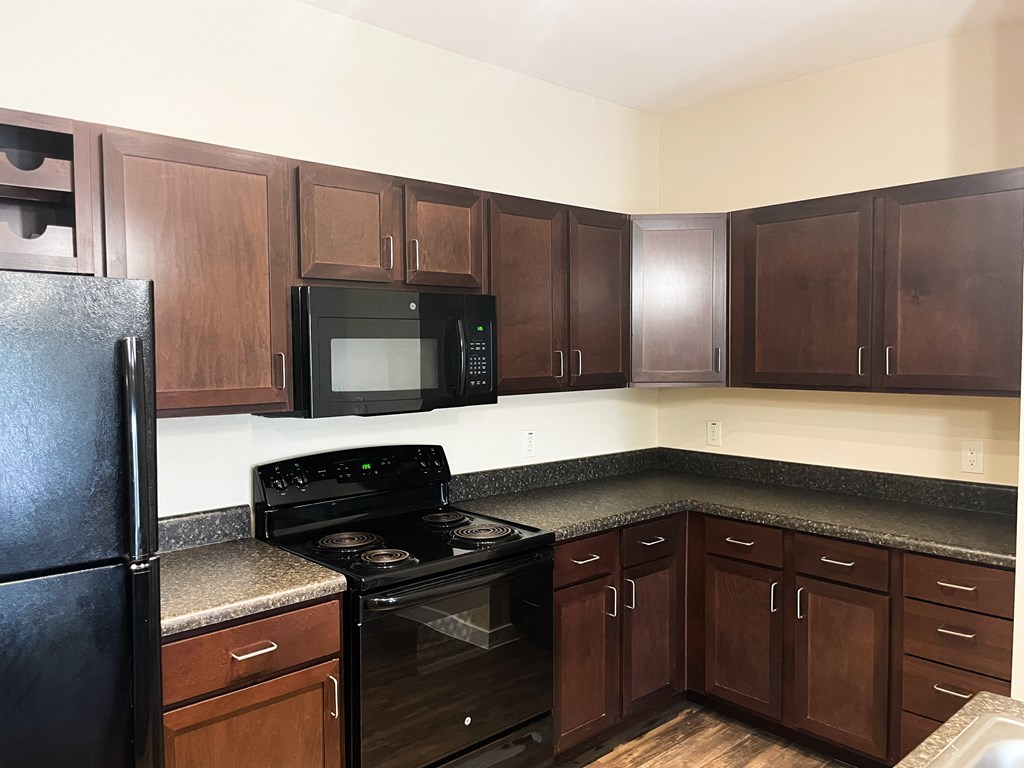 a kitchen with dark wood cabinets and black appliances