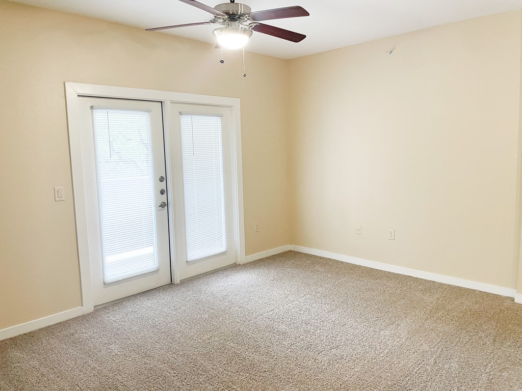a bedroom with a ceiling fan and french doors