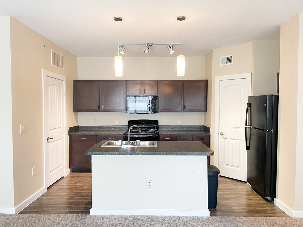 a kitchen with a black refrigerator freezer next to a stove top oven