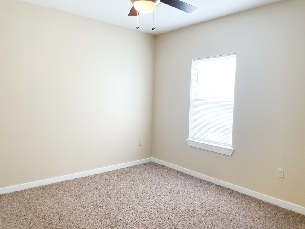 an empty room with a ceiling fan and a window