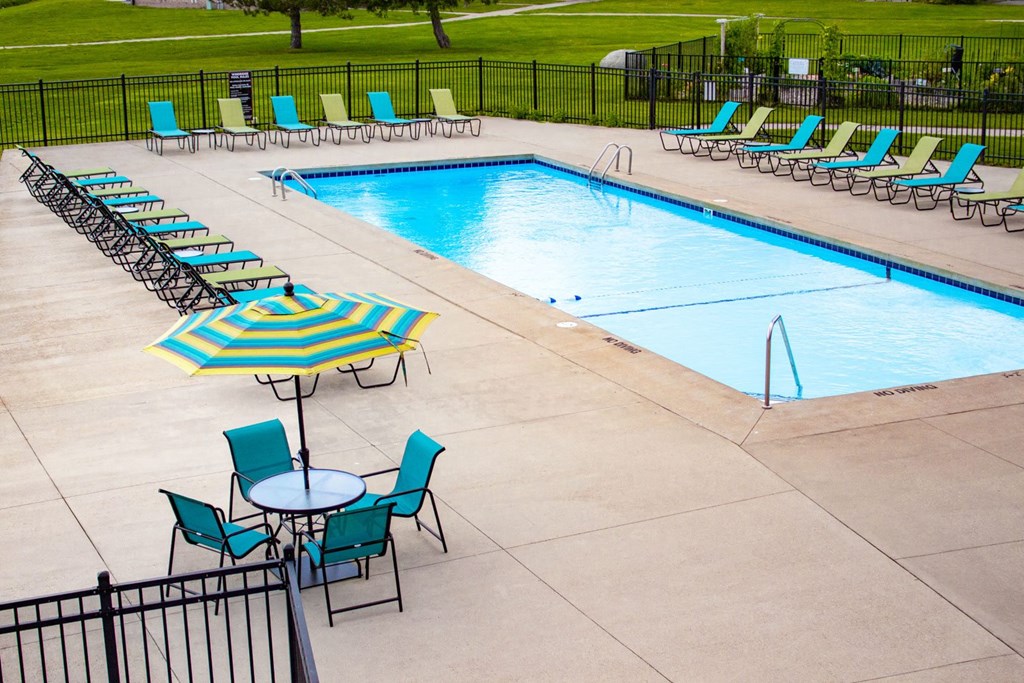 a swimming pool with chairs and a table with an umbrella