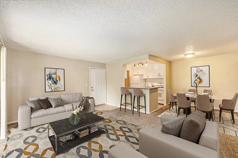 a living room with couches and a coffee table and a dining room and kitchen