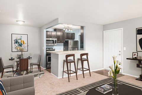 a living room with a kitchen and a bar with stools