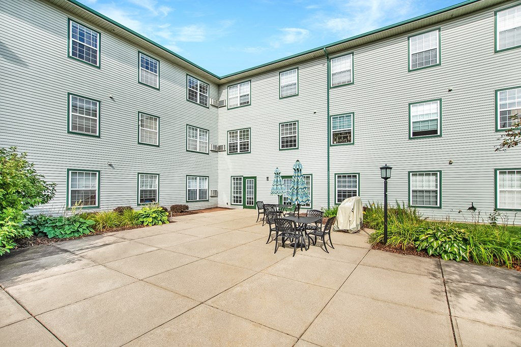 A courtyard with a table and chairs surrounded by apartment buildings.