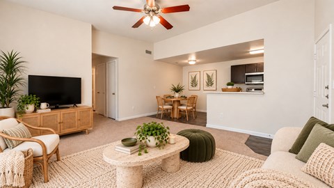A living room with a ceiling fan and a flat screen TV.