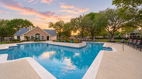 A swimming pool surrounded by trees and a house in the background.