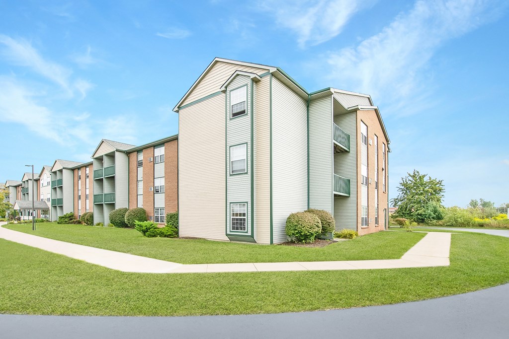 A row of modern apartment buildings with green lawns in front.