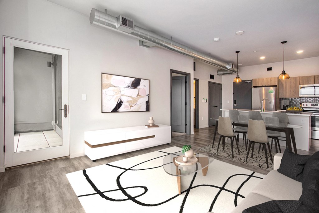 a living room with a white rug and a kitchen with a table and chairs