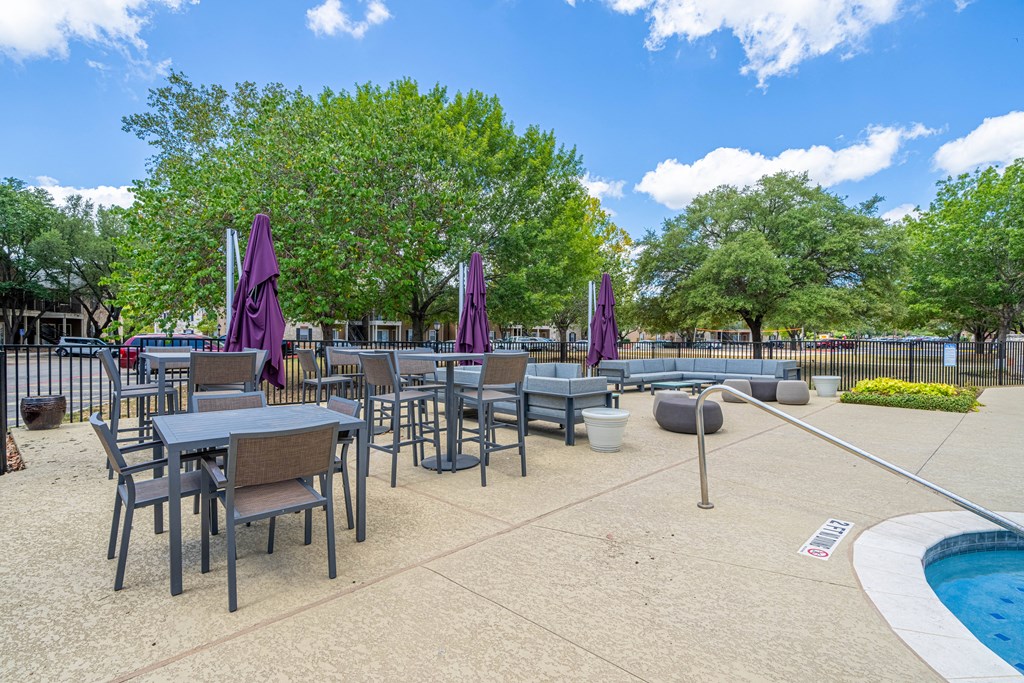 an outdoor patio with tables and chairs and a pool