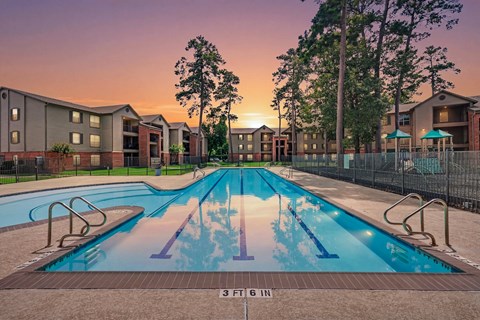 A swimming pool in front of apartment buildings at sunset.