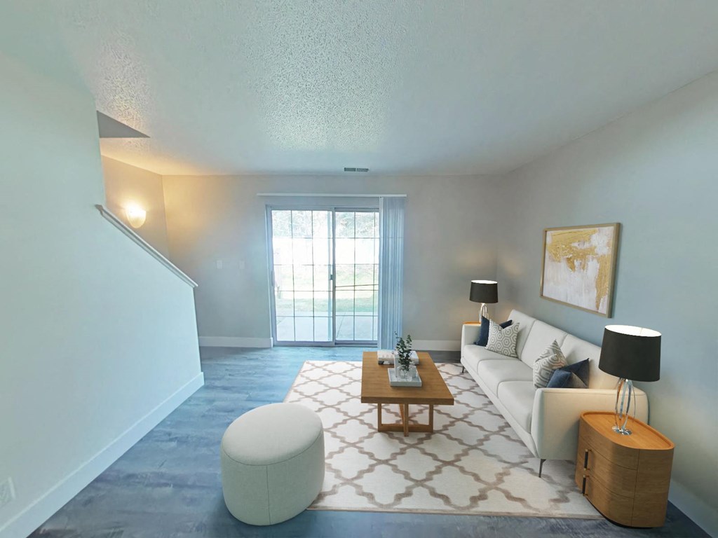 A living room with a white couch, a coffee table, and a large window.