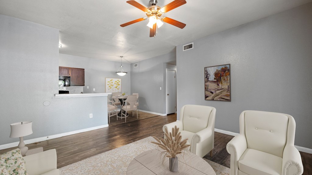 A living room with a ceiling fan and two chairs.